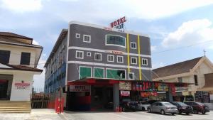 a tall building with cars parked in front of it at Hotel Pinji in Ipoh