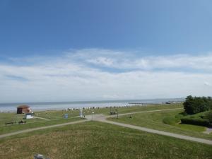 um grupo de pessoas caminhando em um caminho perto do oceano em NordseeResort Hotel & Suite Arche Noah em Horumersiel