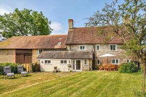 ein altes Steinhaus mit einem Tisch und Stühlen im Hof in der Unterkunft Lower Farm Cottage in Stourton Caundle
