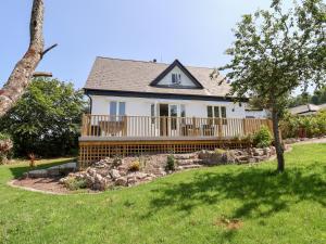 a white house with a deck and a yard at Melbecks in Abergele