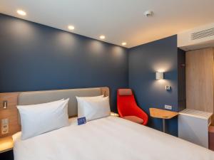 a bedroom with a bed and a red chair at Holiday Inn Express - Hamburg South A7-AS42, an IHG Hotel in Egestorf