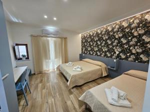 een kamer met 2 bedden en een muur met bloemen bij ZAFFIRO'S HOUSE in Cefalù