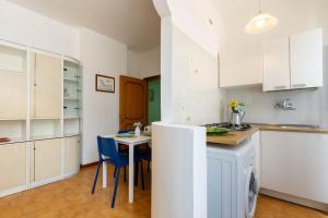 une cuisine avec des placards blancs et une table avec des chaises bleues dans l'établissement Appartamento La Pinetina Trilo PT - MyHo Casa, à Tortoreto Lido