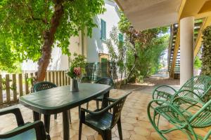 une table et des chaises vertes sur la terrasse dans l'établissement Appartamento La Pinetina Trilo PT - MyHo Casa, à Tortoreto Lido