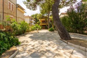 un trottoir avec un arbre au milieu d'un bâtiment dans l'établissement Appartamento La Pinetina Trilo PT - MyHo Casa, à Tortoreto Lido