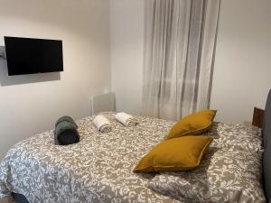 1 dormitorio con 1 cama con almohadas amarillas y TV de pantalla plana en LA TORNADE Villa roof top hypercentre Vichy, en Vichy