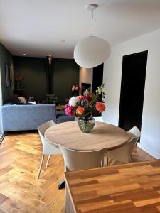 a dining room with a table with a vase of flowers at Casa Clementine - Boutique Guesthouse in Veldhoven