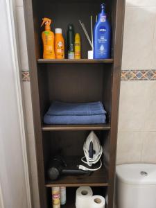 a shelf in a bathroom with a toilet and cleaning products at Studio with garden in Arona +24 photos