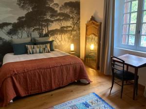 a bedroom with a bed and a table and a window at le secret du chat in Cordes-sur-Ciel
