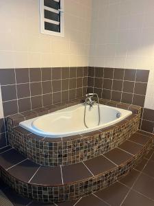 a bath tub in a bathroom with a tiled wall at Le vieux poirier à la Plaine des Cafres in Le Tampon