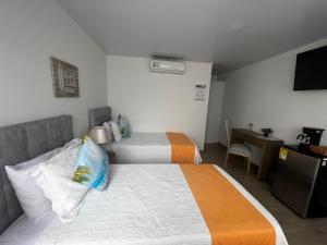 Habitación de hotel con 2 camas y escritorio en Hotel Mar de Corales By CAJASAI, en San Andrés