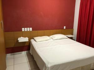 1 dormitorio con cama y pared roja en Golden Dolphin Grand Hotel, en Caldas Novas