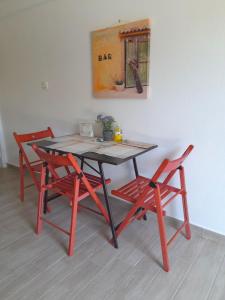 une table avec quatre chaises et un tableau sur le mur dans l'établissement Cosy garden house, à Rafína