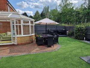 a patio with an umbrella and a table and chairs at Silverstone Stays in Wootton