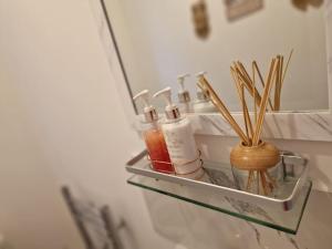 a shelf with bottles and toothbrushes in a bathroom at Silverstone Stays in Wootton