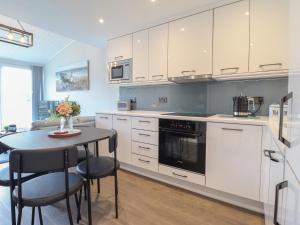a kitchen with white cabinets and a table with chairs at Moelwyn 57D South Snowdon Wharf in Porthmadog +14 photos