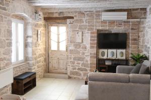a living room with a stone wall with a television at Villa Arte in Bale