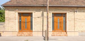 a brick building with two wooden doors on it at Jégmadár & Fekete Gólya Apartmanok in Mosonmagyaróvár