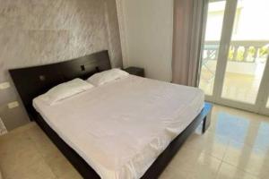 um quarto com uma cama com lençóis brancos e uma janela em Chez Sarah em Beni Khiar
