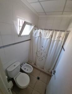 Un baño con inodoro y cortina de ducha. en Departamento centro ciudad, en Mendoza