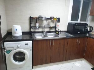 a kitchen with a sink and a washing machine at One BHK in Ajman 