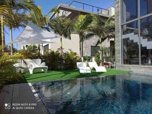 a house with a swimming pool with white chairs and a house at Villa SUN in Ashkelon