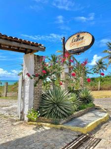 a sign for a restaurant with plants and flowers at Costeira Bacupari in Baía Formosa