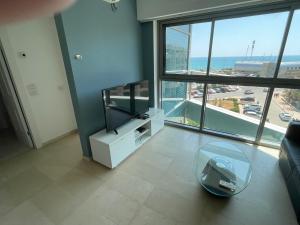 sala de estar con TV y mesa de cristal en אוקיינוס במרינה מלון דירות בעלים פרטיים עם נוף לים מרפסת אחד עד שני חדרי שינה וסלון, en Herzliya