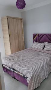um quarto com uma cama com um edredão roxo e branco em Résidence Miftah Sahil Anza em Agadir