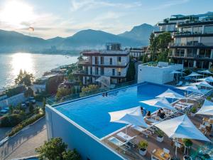 a large swimming pool with white umbrellas on a building at Hotel Harmonia by Dukley in Budva