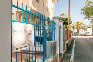 un cancello blu con un cartello sul lato di un edificio di Saporedimare - Affittacamere fronte mare - Narramondo Villas a Tortoreto