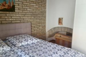 a bedroom with a bed and a brick wall at Kamena Kuca in Crikvenica