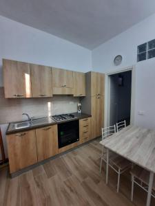 Vista mare rooms في Gasponi: مطبخ مع دواليب خشبية وطاولة خشبية مع الوضوء