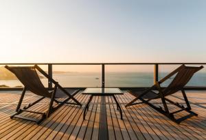 two chairs and a table on a deck with the ocean at L'Agapa Hôtel - Spa Codage in Perros-Guirec