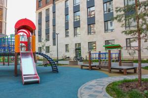 a playground with a slide and benches in front of a building at Lux Apartment Umai in Astana