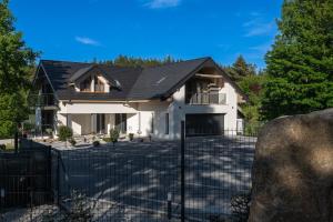 una casa blanca con techo negro en Apartamenty Aspen, en Karpacz