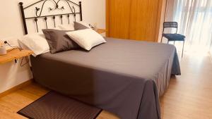 - une chambre dotée d'un grand lit avec des draps et des oreillers gris dans l'établissement LA BALLENERA, à Cangas