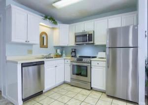 a kitchen with white cabinets and a stainless steel refrigerator at Gulf Shores Plantation Condos in Gulf Shores