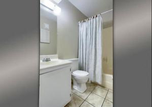een witte badkamer met een toilet en een wastafel bij Gulf Shores Plantation Condos in Gulf Shores