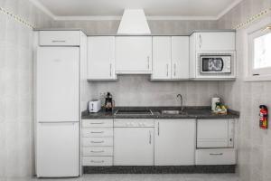 uma cozinha branca com armários brancos e um frigorífico em Caserones 04 em Puerto del Carmen