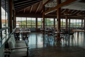 uma sala de jantar com mesas, cadeiras e janelas em Resort Quinta Santa Bárbara OFICIAL em Pirenópolis