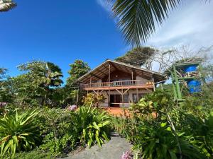 a house with a wrap around porch and a garden at Mompiche Island Hostel in Mompiche