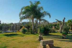 un parc avec une aire de jeux avec des palmiers et un banc dans l'établissement La Botte, à Giurdignano