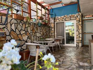 a restaurant with tables and chairs and a stone wall at Çeşme Flowers Hotel in Ildır