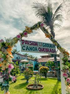 a sign for a resort with a palm tree at Pousada La Goduria in Canoa Quebrada