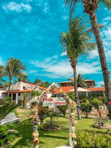 een bord voor een resort met palmbomen bij Pousada La Goduria in Canoa Quebrada