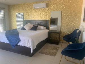 a bedroom with a bed with a mirror and two chairs at San Miguel Cabañas in Valle de Guadalupe