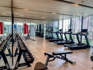 une salle de sport avec une rangée de tapis de course et de machines dans l'établissement Srinakarin Lasalle 2 BR Bangkok, à Bangna