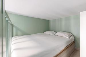 a white bed in a room with a green wall at My CASA - SAINT SIAGRE 3 in Nice