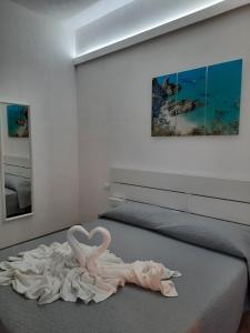 Vista mare rooms في Gasponi: غرفة بها بجعة بيضاء على سرير